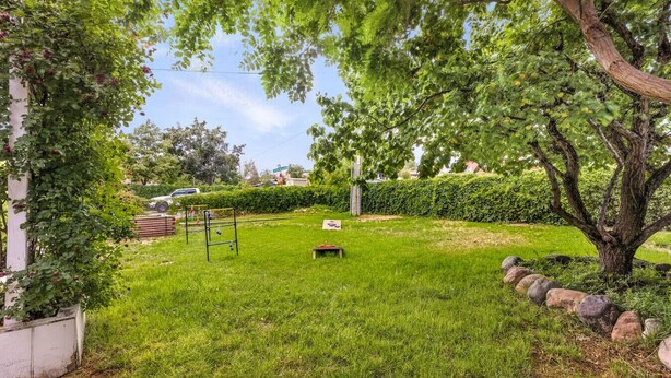 A well-maintained garden with a grassy lawn, a climbing plant, a metal structure, and a large tree. - Boutique Estate - Hot Tub | Firepit | Fam Fun (Payson)