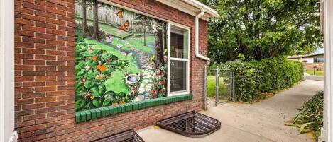 Un edificio de ladrillo con un mural que representa una escena de jardín.