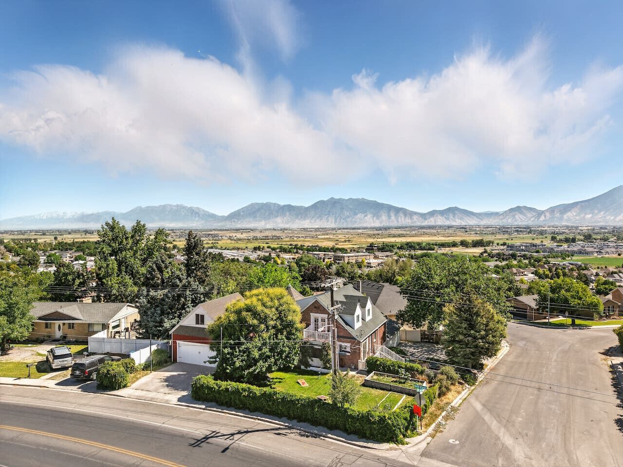 A residential area with houses, a road, and mountains in the background.
