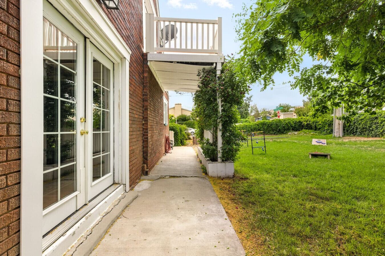 A residential property with a brick exterior, a covered porch, a concrete pathway, and a well-maintained lawn.