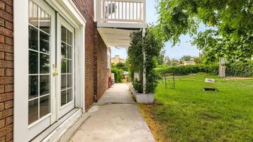 A residential property with a brick exterior, a covered porch, a concrete pathway, and a well-maintained lawn.