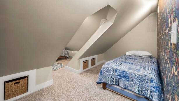 A bedroom with a sloped ceiling, a bed with patterned bedding, a small window, and a wall-mounted artwork. - Boutique Estate - Hot Tub | Firepit | Fam Fun (Payson)