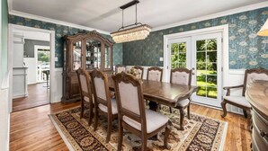 A dining room with a wooden table, six chairs, a chandelier, and a large mirror. - Boutique Estate - Hot Tub | Firepit | Fam Fun (Payson)