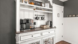 A kitchen with a white cabinet, a coffee machine, a kettle, and a tea box. - Boutique Estate - Hot Tub | Firepit | Fam Fun (Payson)