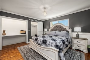 Une chambre à coucher avec un grand lit, une table de chevet, une commode, une armoire et un lustre.