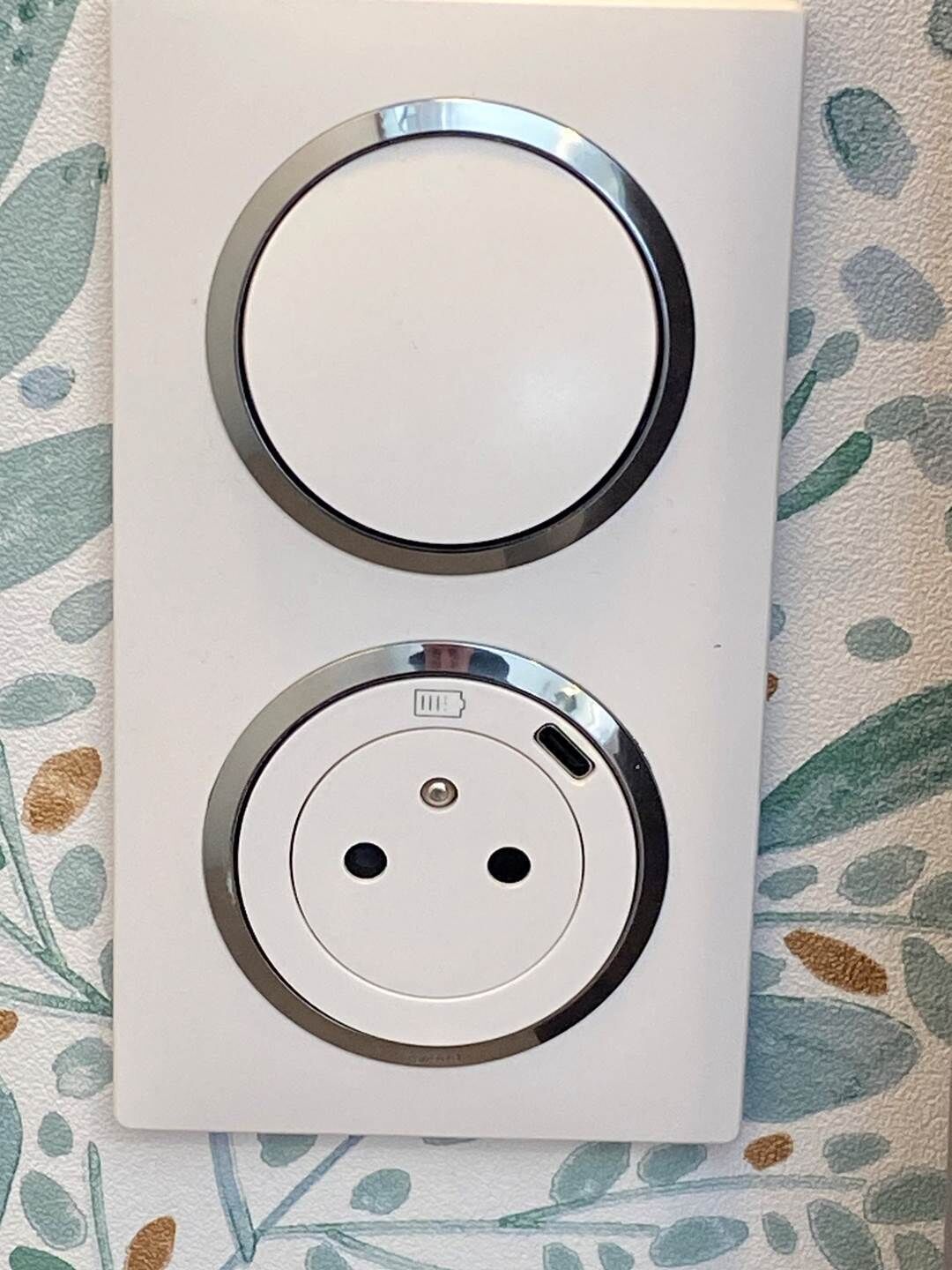 A white electrical outlet with two circular sockets and a USB port.
