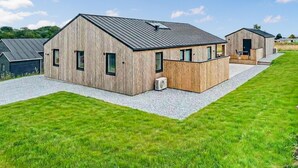 Un bâtiment moderne en bois, doté d’un toit en pente et d’une petite structure adjacente.