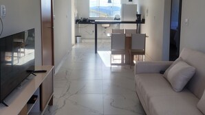 Un salon moderne doté d’un téléviseur à écran plat, d’un canapé et d’un coin repas avec des chaises et une table.