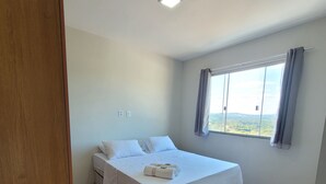 Une chambre à coucher avec un lit, une fenêtre avec des rideaux et une vue sur l’extérieur.