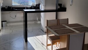 Une cuisine moderne dotée d’une grande fenêtre, d’un réfrigérateur et d’un coin repas avec une table et des chaises.