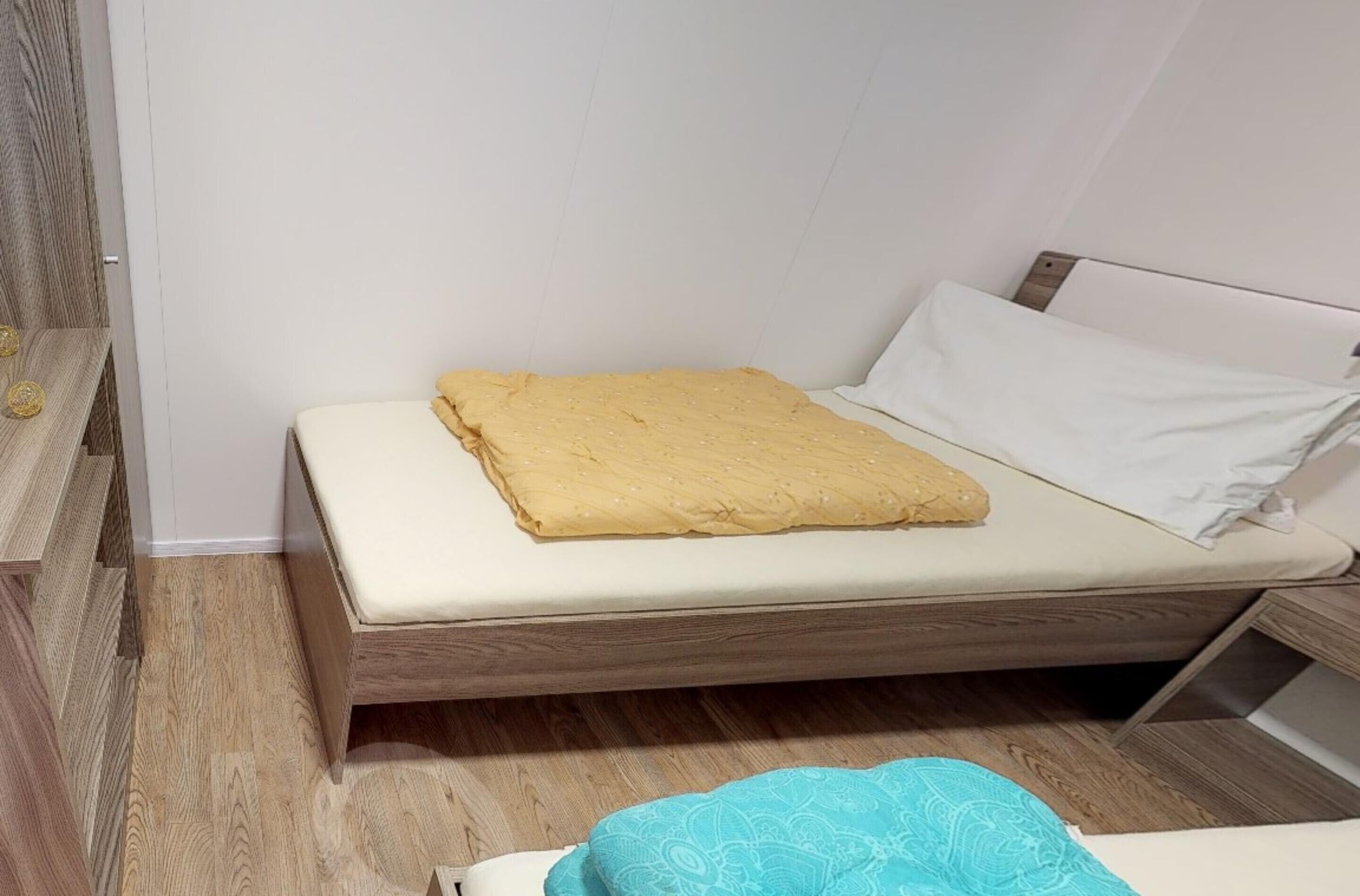 Una habitación pequeña con una cama individual, estructura de madera y colchón color beige.
