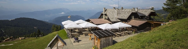 A mountain lodge with outdoor seating and a view of the surrounding mountains.