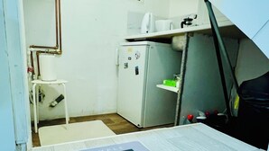 A compact kitchen with a refrigerator, a small table, and a microwave. There's a sign indicating no smoking.