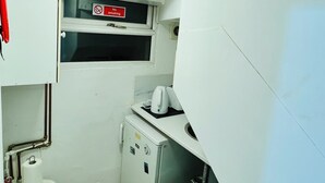 A compact kitchen with a refrigerator, a microwave, and a small sink. There is a window with a 'No Smoking' sign above it.