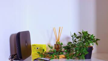 A desk with a laptop, a yellow box, a potted plant, and a reed diffuser.