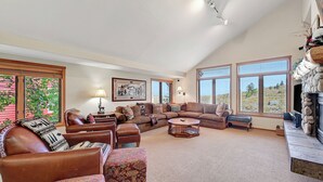A spacious living room with a high ceiling, large windows, a fireplace, and a cozy seating area. - Snowcreek 811- Beautiful views, Spacious (Mammoth Lakes)