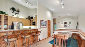 A modern kitchen with wooden cabinets, a bar area with stools, and a dining table with benches. - Snowcreek 811- Beautiful views, Spacious (Mammoth Lakes)