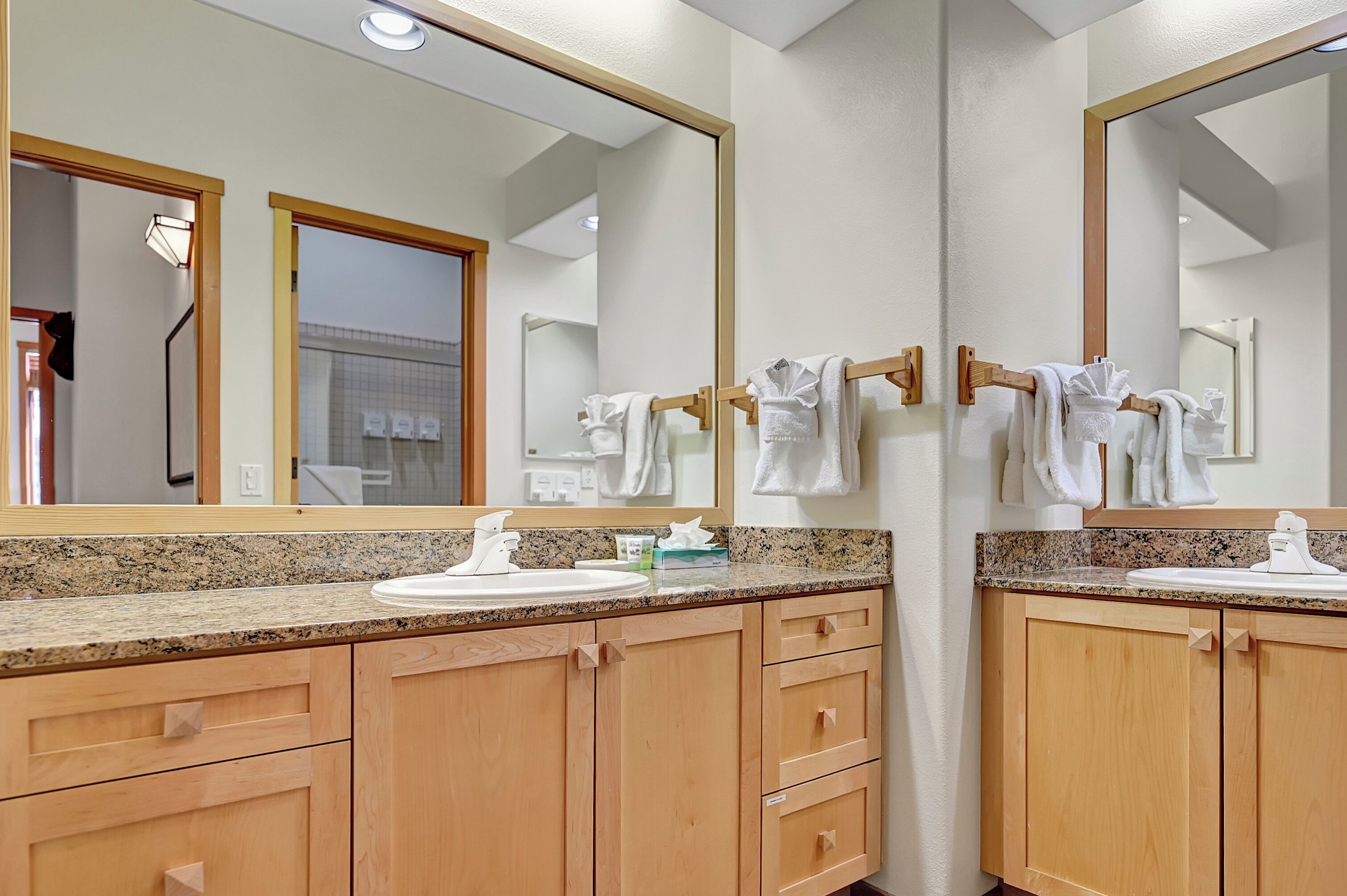 A bathroom with two sinks, wooden cabinets, and a large mirror.