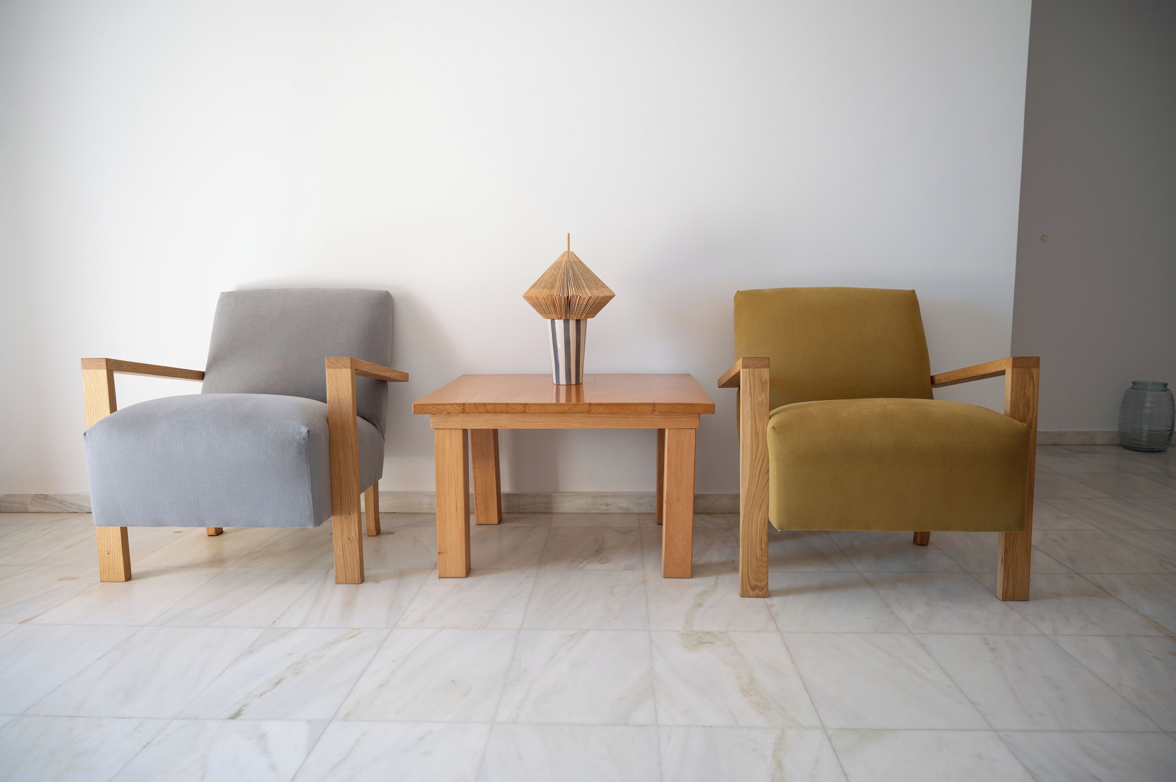 Una habitación con tres sillas, una mesita y un jarrón.