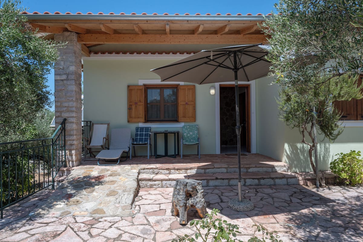 A stone patio with outdoor seating, a wooden pergola, and a stone table.