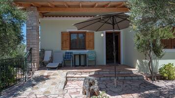 A stone patio with outdoor seating, a wooden pergola, and a stone table.