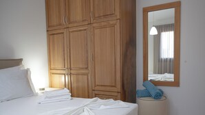 A hotel room with a bed, wooden wardrobe, and a mirror. - Terra Ionian (Pyrgos)