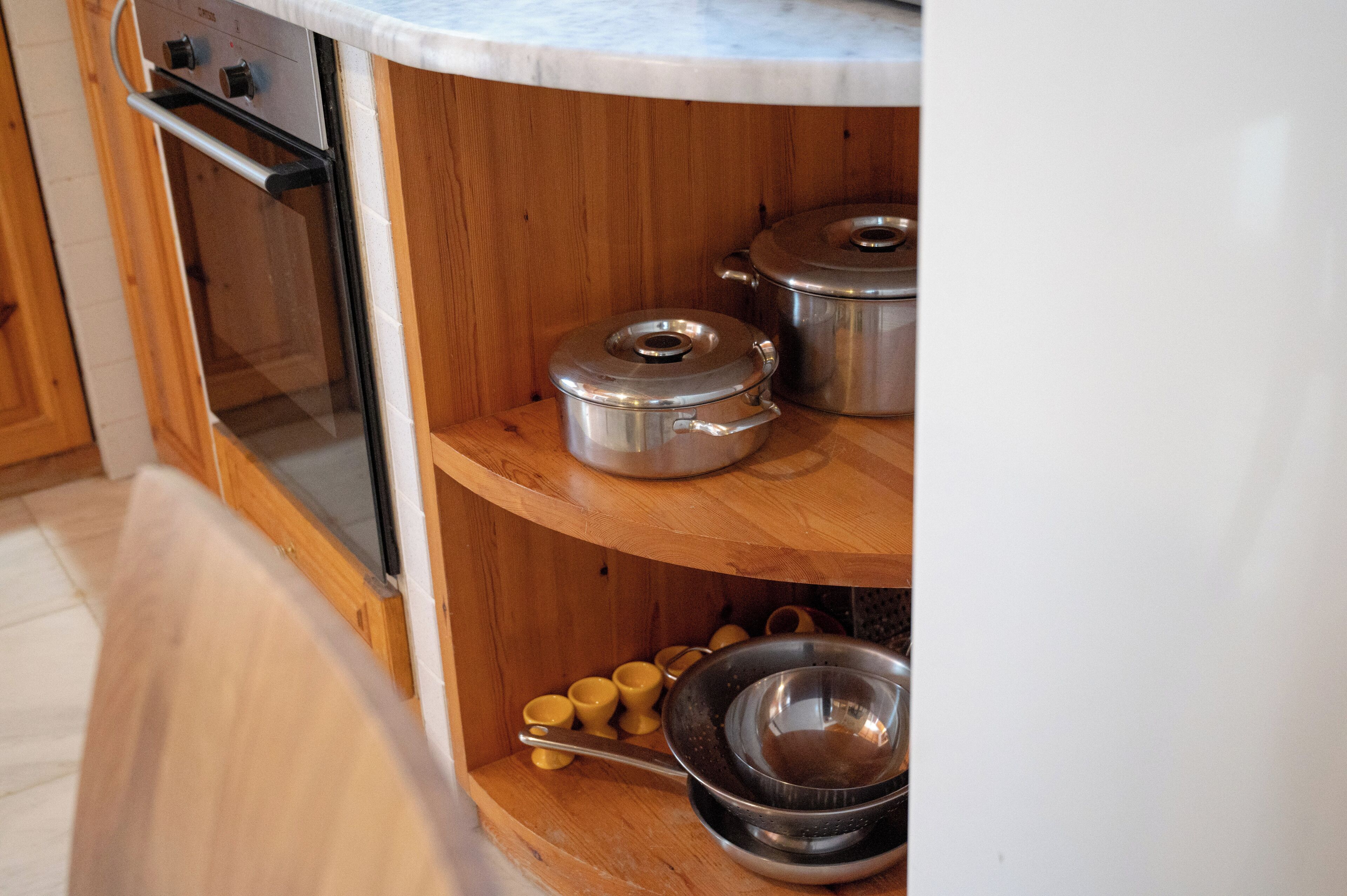 A kitchen with wooden cabinets, stainless steel cookware, and a built-in oven.