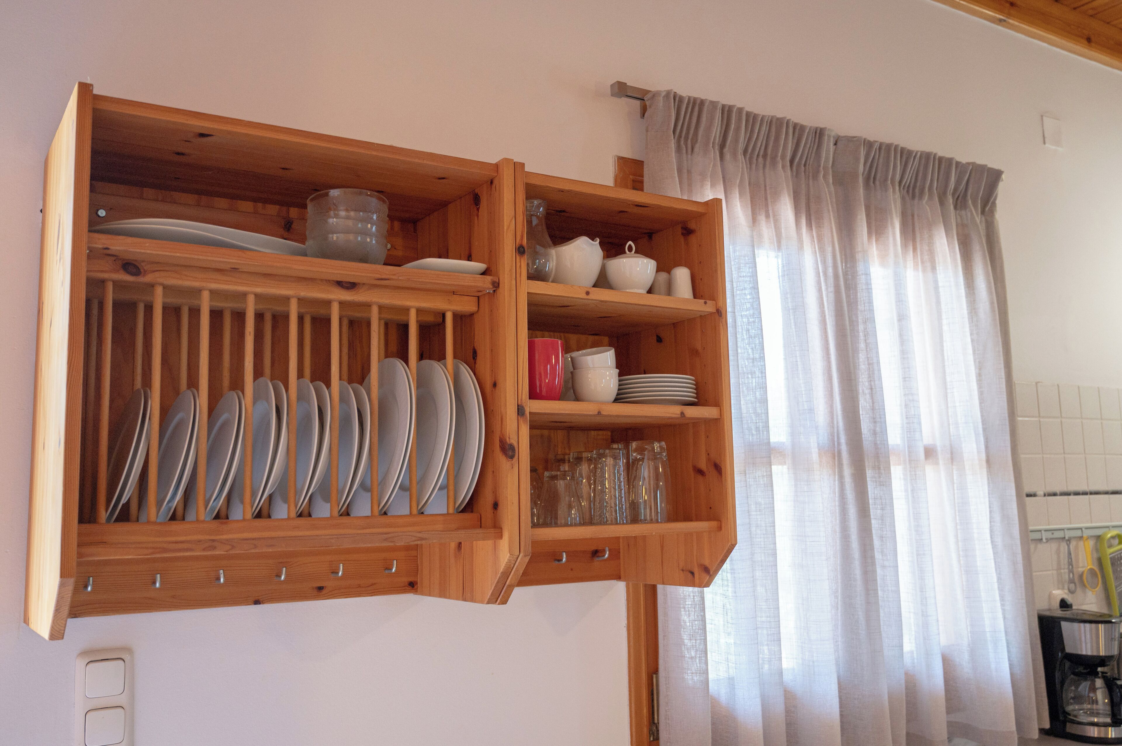 Un armario de cocina de madera con vajilla y cristalería.
