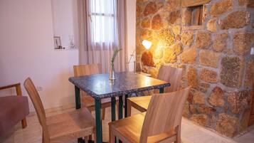 A dining area with a stone wall, a table with chairs, and a vase with a plant.
