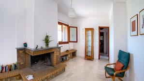 A living room with a fireplace, a bookshelf, a green chair, and a hallway leading to another room. - Terra Ionian (Pyrgos)