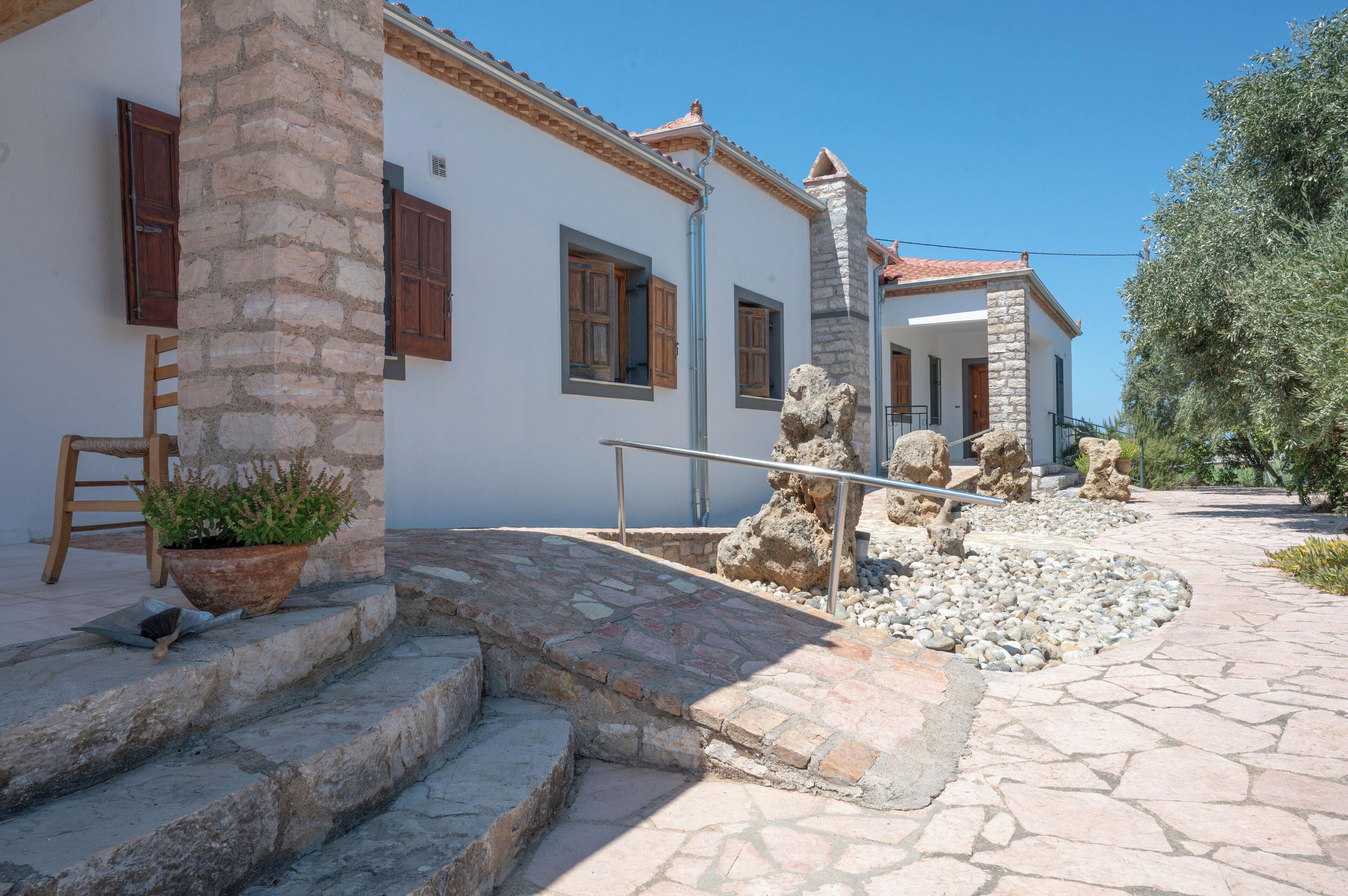 A stone staircase leading to a white building with wooden shutters and a potted plant.