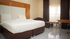 Una habitación de hotel con una cama grande, un cabecero de madera, un escritorio y una silla.