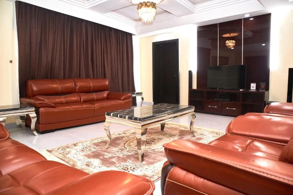 A living room with a brown leather sofa, a glass coffee table, and a television on a wooden cabinet.