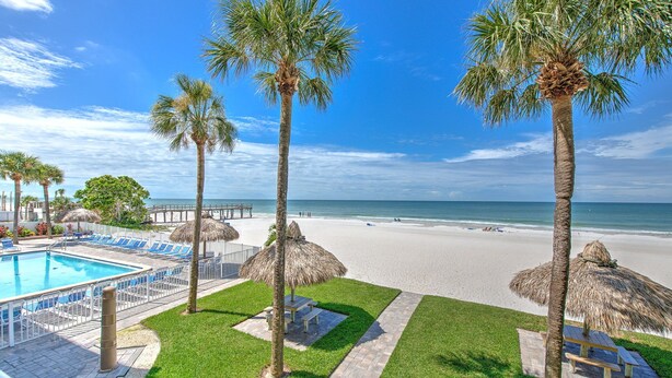 A pool area with lounge chairs, palm trees, and a beach view. - Sea Oats 106: 3  BR, 2  BA Condominium in Redington Shores, Sleeps 8 (Redington Shores)