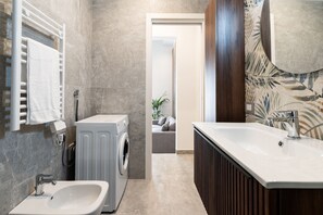 Ein modernes Badezimmer mit integrierter Waschmaschine, einem Waschbecken und einer Duschkabine.