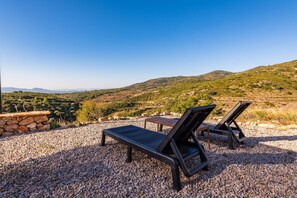 Dos sillones de relax sobre un terreno de grava con vistas a un paisaje montañoso.