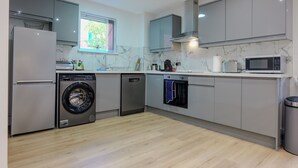 A modern kitchen with a washing machine, dishwasher, oven, and microwave.