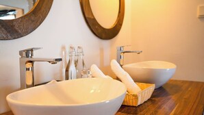 Une salle de bain avec deux vasques en céramique blanche, un meuble-lavabo en bois et un miroir.