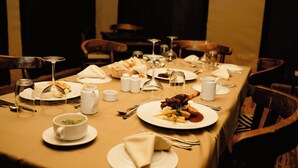 Une table à manger dressée pour un repas, avec des assiettes, des couverts et des verres.