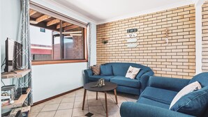 Una sala de estar con un sofá azul, una mesa redonda pequeña y una pared de ladrillo.