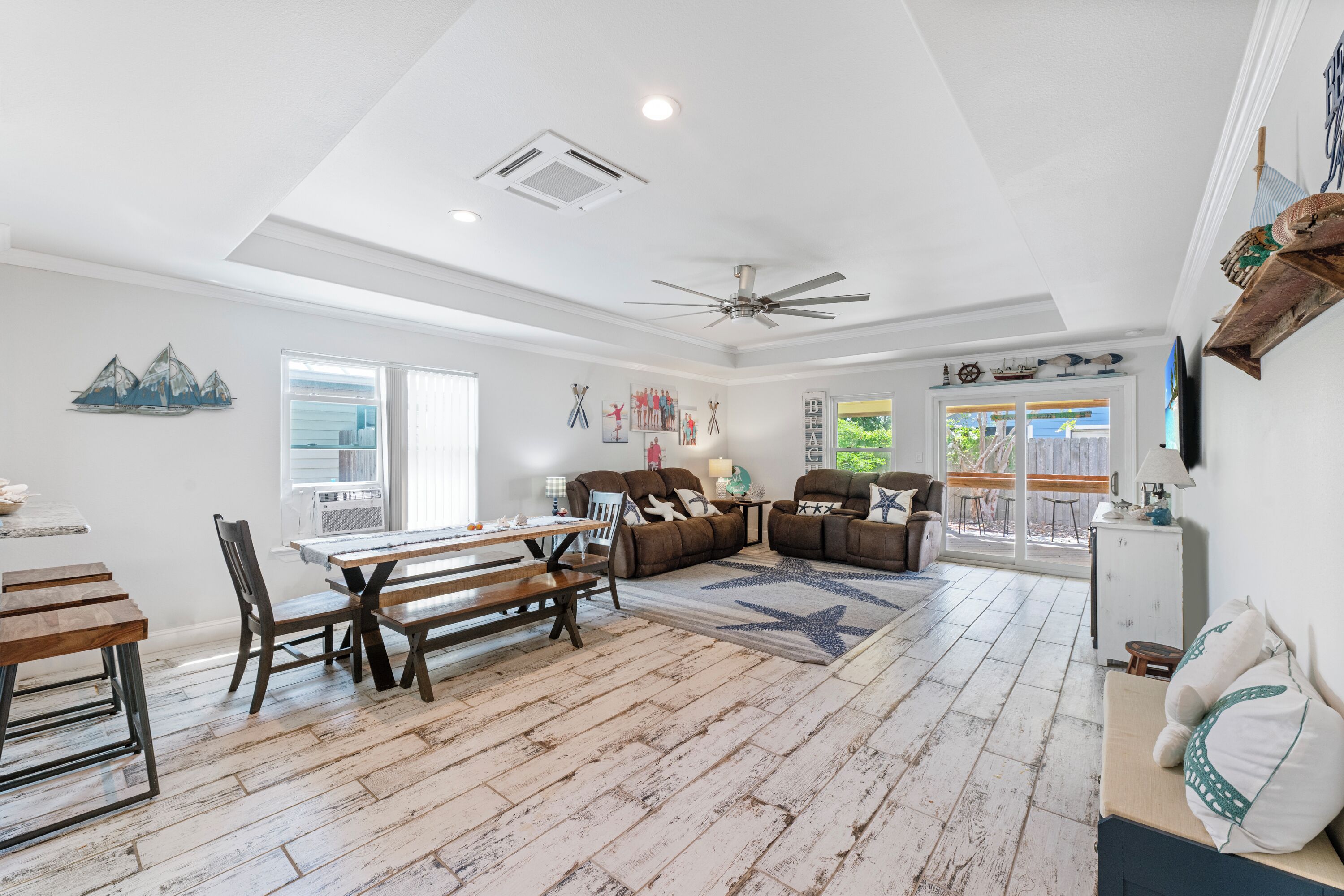 A spacious living area with a dining table, sofas, and a ceiling fan.