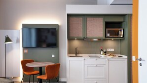 A compact kitchen with a microwave, sink, and a small dining area with two chairs. - HUB Apartments – St. Georg (Hamburg)
