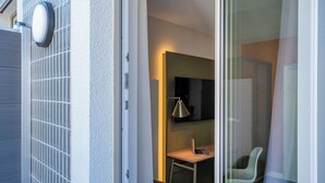 A modern interior with a sliding glass door leading to a room with a desk, chair, and a mounted TV. - HUB Apartments – St. Georg (Hamburg)