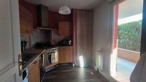 A compact kitchen with wooden cabinets, a stove, an oven, and a microwave.