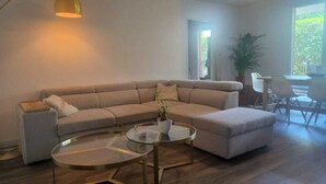 A modern living room with a sectional sofa, a glass coffee table, and a small side table.