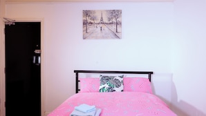 A bedroom with a bed, a door, and a painting on the wall.