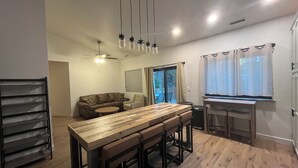 A modern kitchen with a wooden table and bar stools, a ceiling fan, and pendant lights. - *Just Listed* Alpine Retreat with A/C and hot Tub! (Flagstaff)