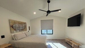 A bedroom with a bed, a ceiling fan, a TV, a window with blinds, and a wooden floor. - *Just Listed* Alpine Retreat with A/C and hot Tub! (Flagstaff)