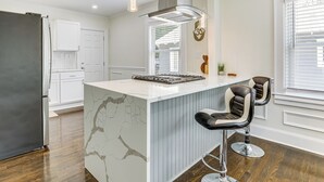 A modern kitchen with a marble island, two bar stools, a stainless steel refrigerator, and pendant lighting. - 4 Mi to Intl Soccer & Dtwn Fun: Modern ATL Home (Atlanta)