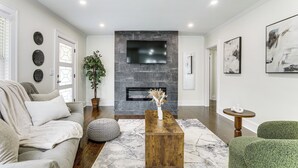 A modern living room with a fireplace, a sofa, a coffee table, and artwork on the walls. - 4 Mi to Intl Soccer & Dtwn Fun: Modern ATL Home (Atlanta)